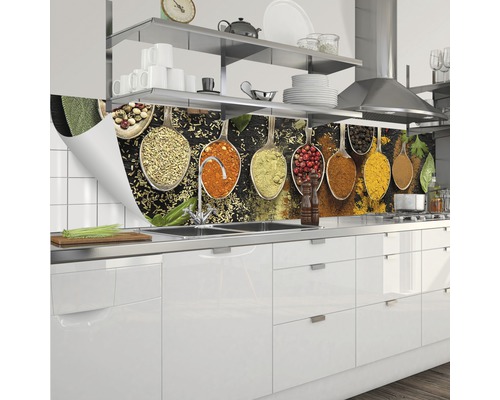 Stänkskydd med kryddmotiv i skedar i vitt kök.