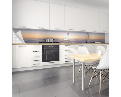 Ljust kök med stänkskydd med vattenmotiv bakom spishällen