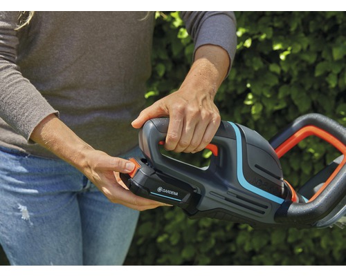 En person håller en batteridriven häcksax av märket Gardena.