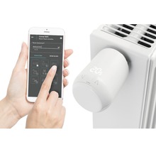 Smart radiatortermostat med appstyrning monterad på radiatorn och smartphone för styrning