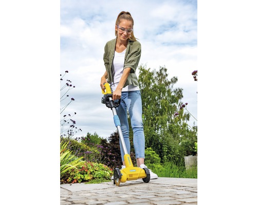 En kvinna använder en kantskärare i trädgården.