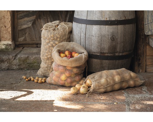 Jutesäckar fyllda med äpplen, lök och potatis framför trätunna