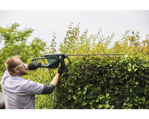Man klipper häck med en häcksax av märket Bosch