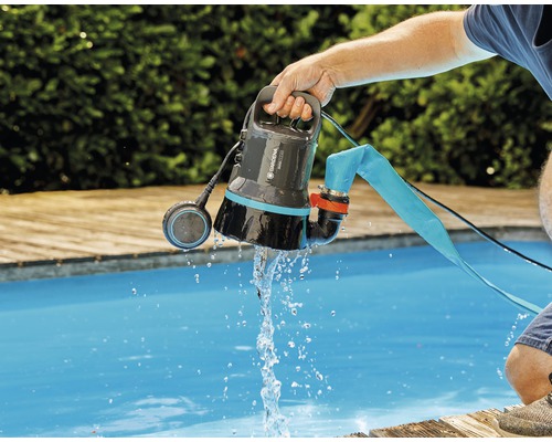 En Gardena smutsvattenpump hålls ovanför en pool medan vatten strömmar ut ur den.