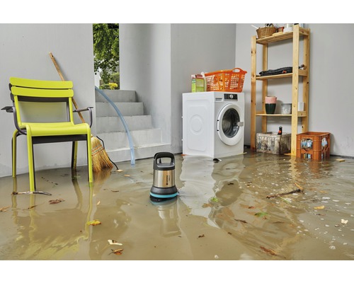 Översvämmad källare med smutsigt vatten och dränkpump bredvid tvättmaskin, hylla och stol