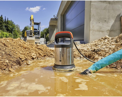 Gardena dränkbar smutsvattenpump i bruk i en byggrop med grävmaskin i bakgrunden.