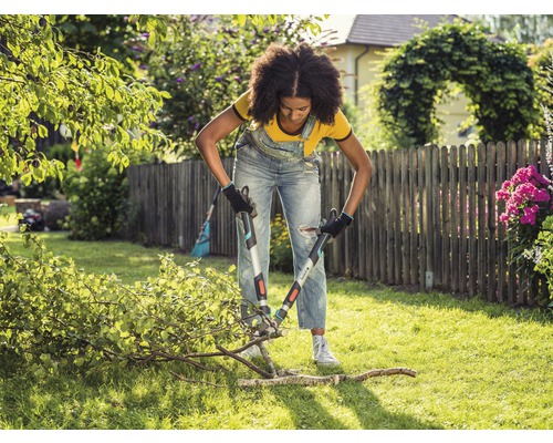 Kvinna beskär grenar med en grensax i trädgården.
