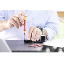 Hantverkare arbetar med skruvmejsel på elektronisk apparat