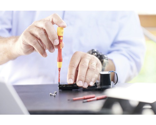 Hantverkare arbetar med skruvmejsel på elektronisk apparat