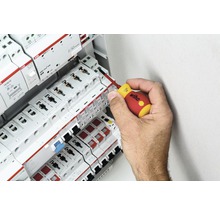 En hand använder en skruvmejsel på en säkringsdosa med ABB-komponenter.