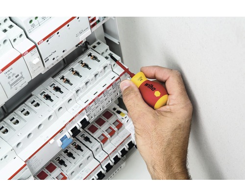 En hand använder en skruvmejsel på en säkringsdosa med ABB-komponenter.