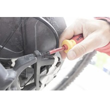 En person använder en skruvmejsel på en cykel.