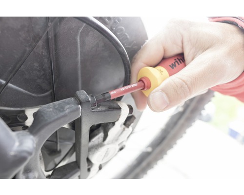 En person använder en skruvmejsel på en cykel.