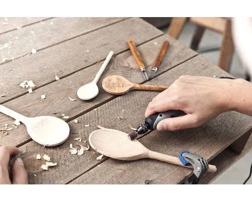 Hantverksscen med träskedar, snidverktyg och roterande verktyg på en träyta