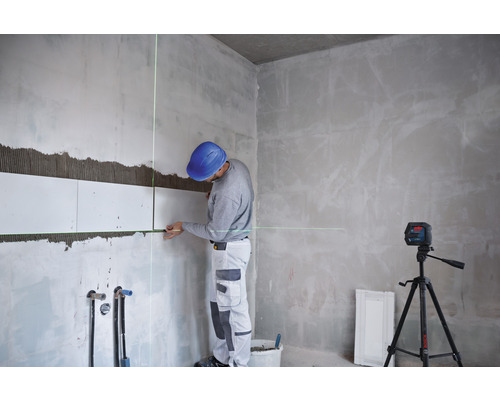 Hantverkare lägger plattor med en krysslaser på en byggarbetsplats