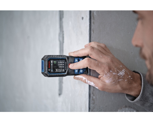 En person använder en Bosch avståndsmätare på en vägg för mätning.