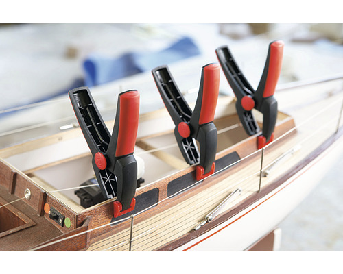 Tre fjäderklämmor fästa på en träfartygsmodell