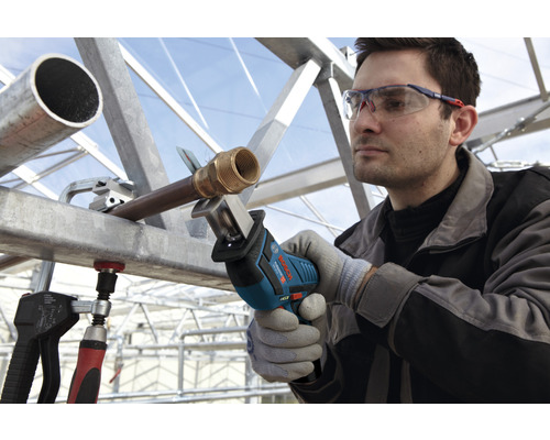 En man sågar ett rör med en tigersåg från Bosch, medan han bär skyddsglasögon och handskar.