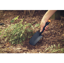 Närbild av en person som arbetar i trädgården med en planteringsspade.