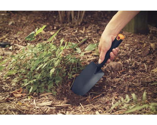 Närbild av en person som arbetar i trädgården med en planteringsspade.