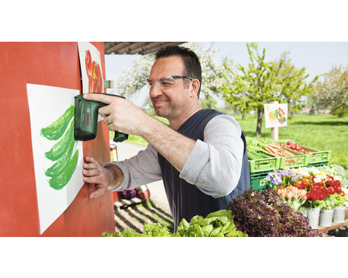 En man fäster ett papper med en batteridriven häftpistol på en grönsaksdisk.