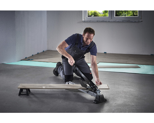 Man skär laminat med en laminatskärare.