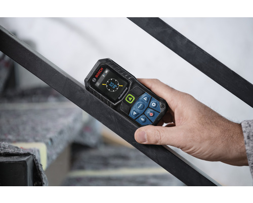 Hand håller digital lutningsmätare från Bosch på ett räcke