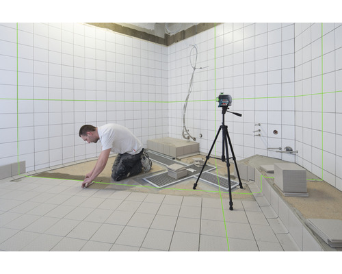 Plattsättare som arbetar med en linjelaser i ett badrum med vita plattor