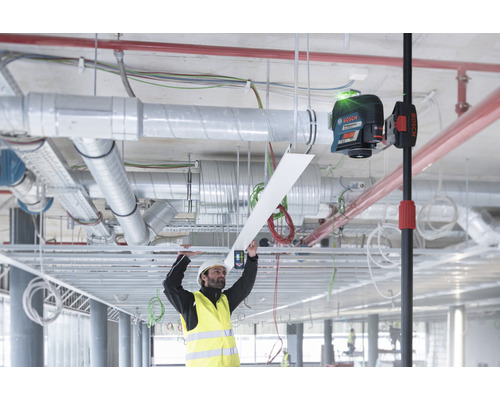 Interiörbild av en byggarbetsplats med en arbetare och en linjelaser för inriktning