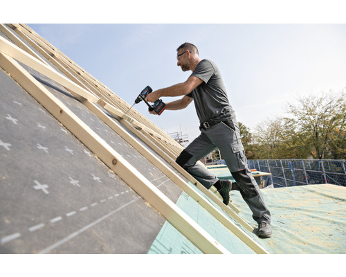 Hantverkare som arbetar med en sladdlös skruvdragare på en takkonstruktion.