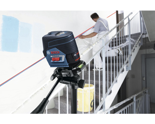 Bosch logotyp. Krysslaser på stativ med hantverkare i trapphus.