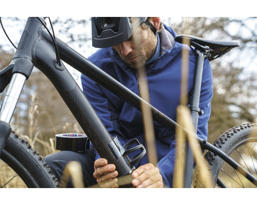 Man fäster en flaskhållare med tejp på en cykel