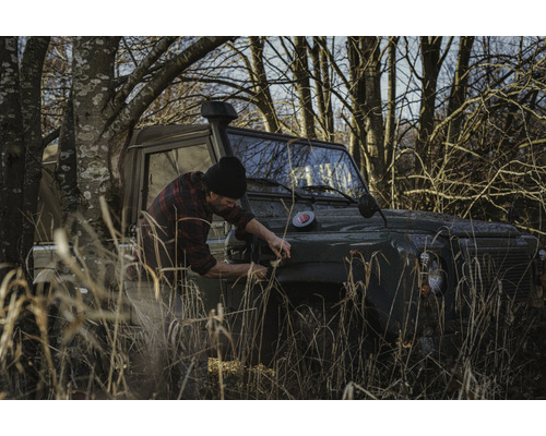 Man öppnar motorhuven på en terrängbil i naturen