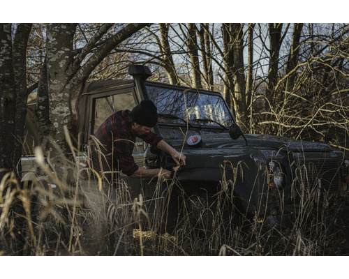 Man reparerar en terrängbil i naturen