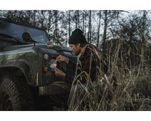 Man fäster tejp på strålkastaren på en terrängbil
