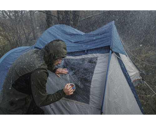 Person rengör tältfönster i regnigt väder.