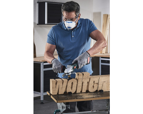 En man formar ordet trä med en träfrässkiva.