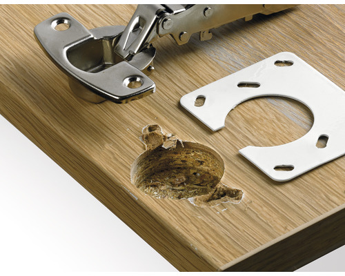 Möbelskåpsgångjärn med monteringsplatta på en träyta och borrhål