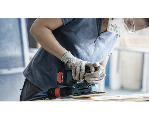 En person slipar trä med en sladdlös vibrerande slipmaskin och bär skyddshandskar och ett dammfilter.