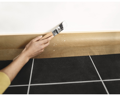 Måla en vägg med pensel och tejp för att skydda golvet