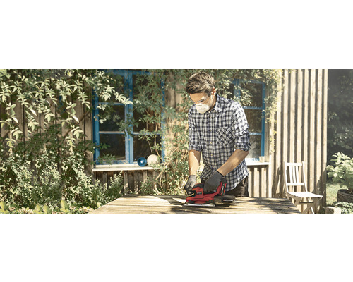 En man slipar trä med en elektrisk slipmaskin utomhus