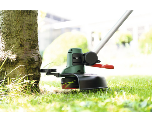 Grästrimmer i drift vid ett träd
