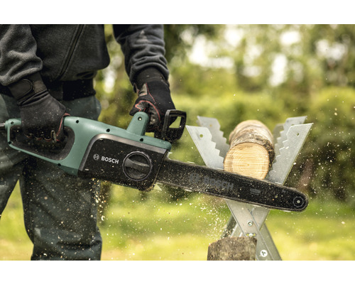 Man sågar en träbit med en elektrisk Bosch motorsåg på ett sågbord