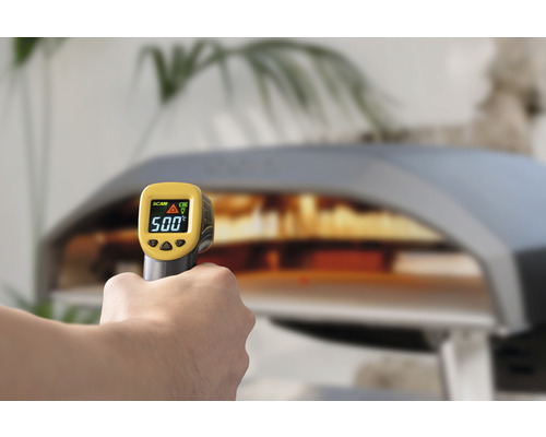 Hand håller en infraröd termometer framför en pizzaugn och visar 500 grader.