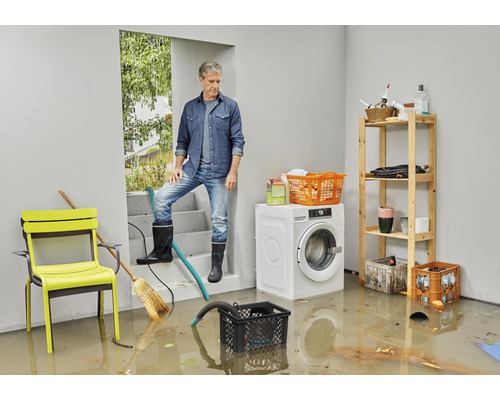 Översvämmad källare med man på trappan, tvättmaskin och hyllor