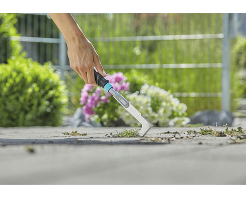 Närbild av en person som tar bort ogräs med en fogskrapa