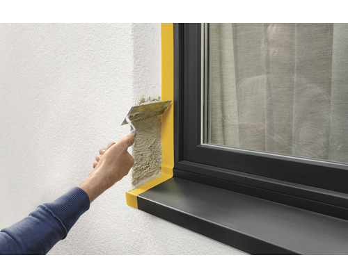 Putsning av en vägg bredvid ett fönster med maskeringstejp