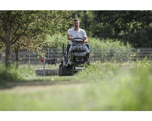 Man kör en åkgräsklippare på ett fält