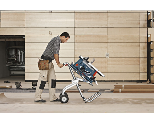 Man transporterar en bordsåg med en transportvagn på en byggarbetsplats