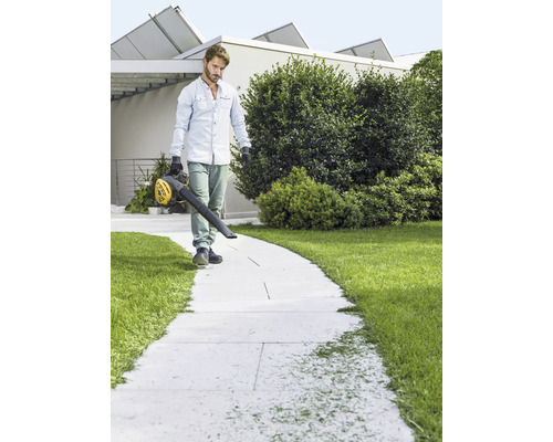 Man rengör gångväg med en lövblås